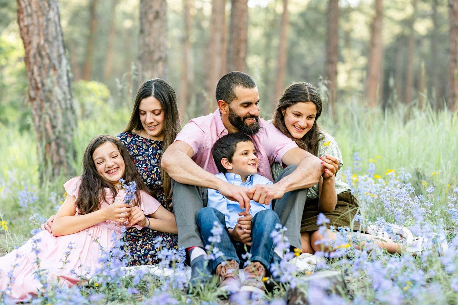 Parents and their three children sit among the wildflowers during their family session in Colorado Springs.