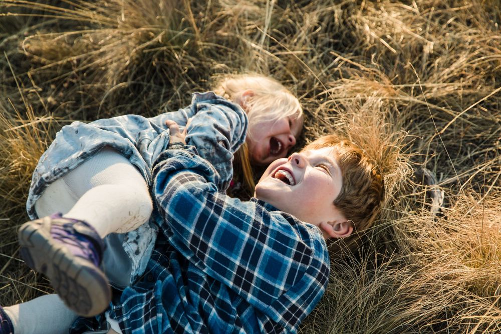 siblings playing at sunset in field, laughing, breckenridge, dillon, summit county, colorado