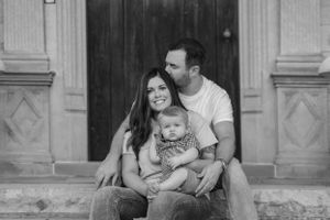 A husband lovingly kisses his wife and child