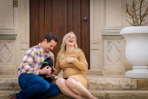 A husband wife share a huge candid laugh at their tiny dog.