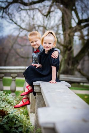 Seated on a stone railing, these twins are dressed in striking red shoes.