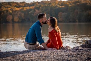 An engaged couple make the most of the setting sun and Autumn colors as a perfect time to kiss