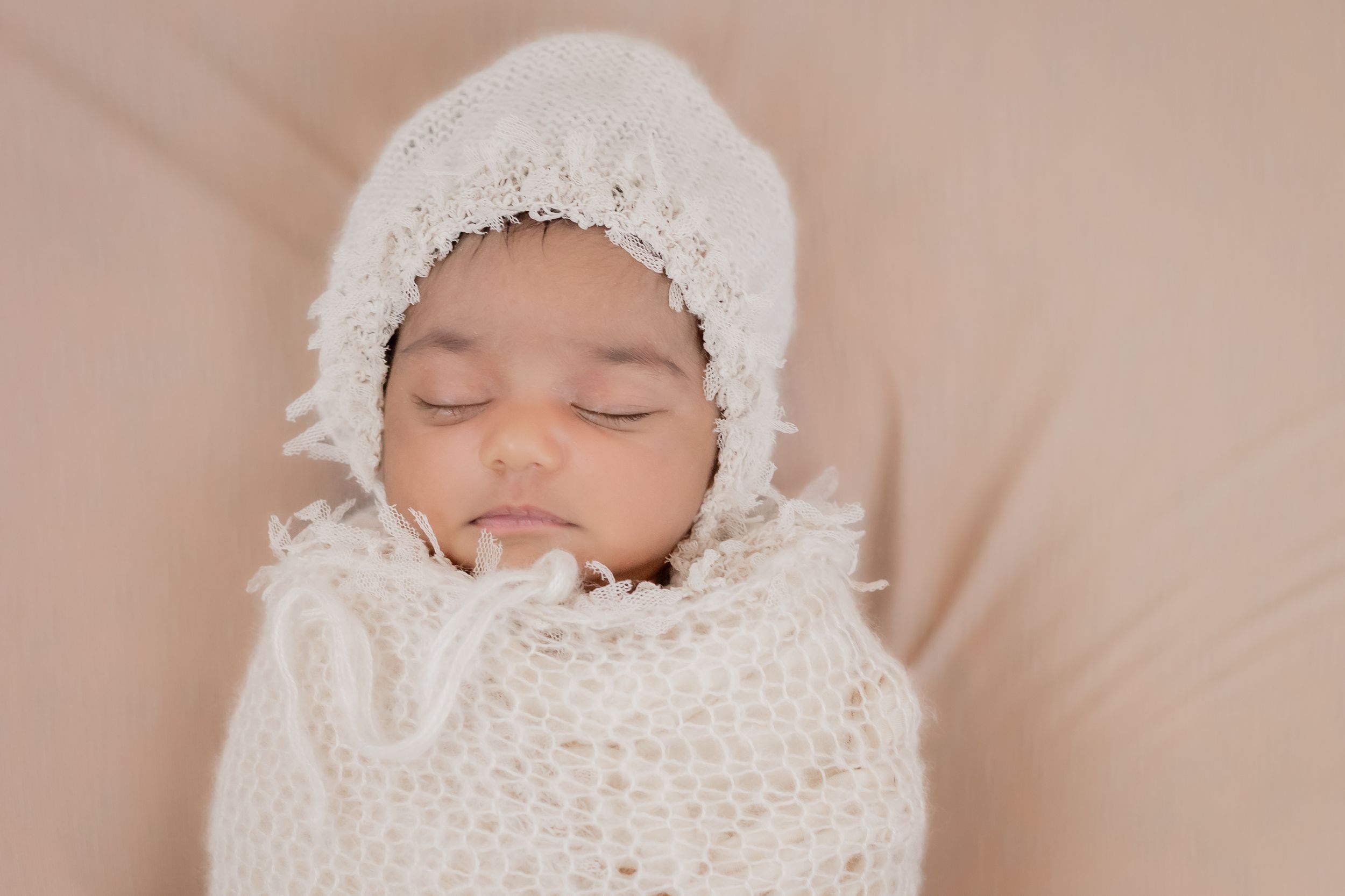 sleeping baby looks cozy in a soft cream wrap sleeping soundly