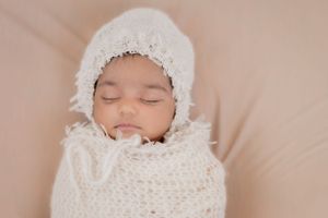 sleeping baby looks cozy in a soft cream wrap sleeping soundly