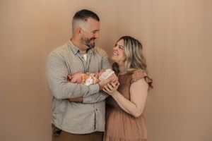 a new mother and father hold their baby in this newborn session