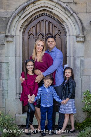 a family hugs and smiles underneath the arch of a wooden doorway