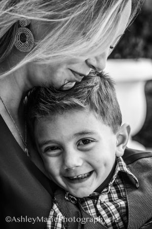 a little boy snuggles close to his mother while she smiles down at him