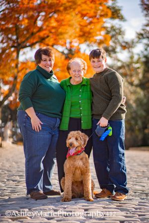 A family embraces on a cobblestone street with a golden retriever sitting front and center