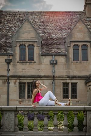 posed on a stone railing with a mansion reaching to the sky, this senior portrait is classy and edgy