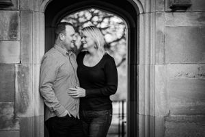 A husband and wife steal a kiss in a stone archway