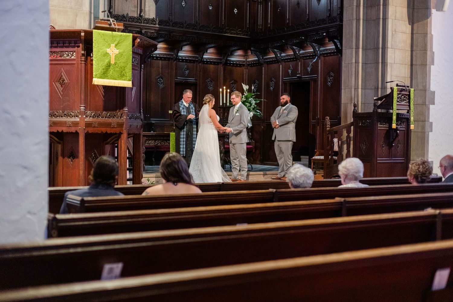 Church interior with wooden pews and altar area illuminated by natural light.