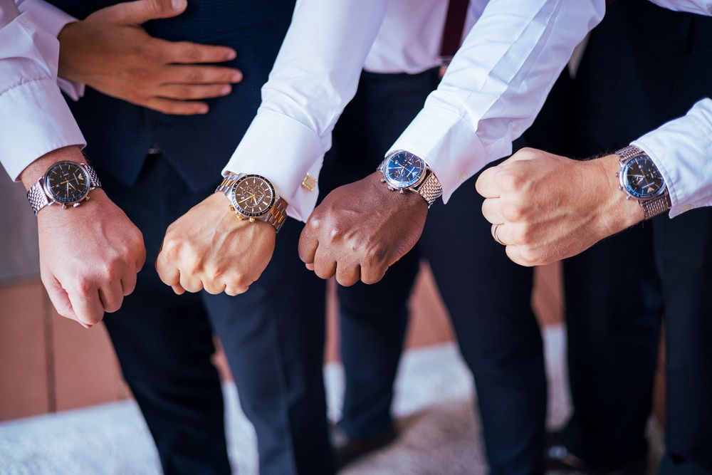 Several hands come together to show off matching luxury watches in a group shot.