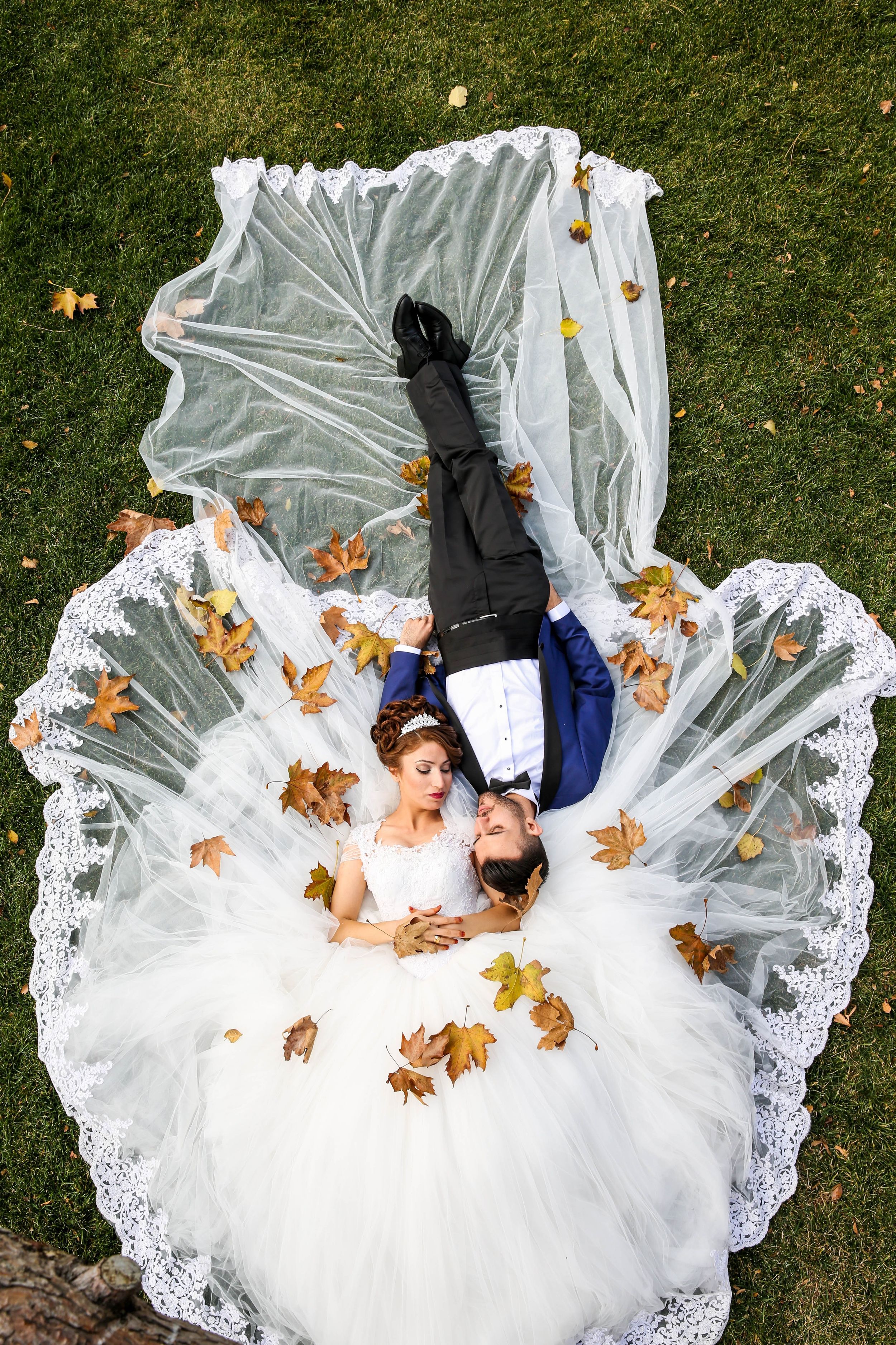 Bride and Groom laying down on the grass while looking at each other in autumn