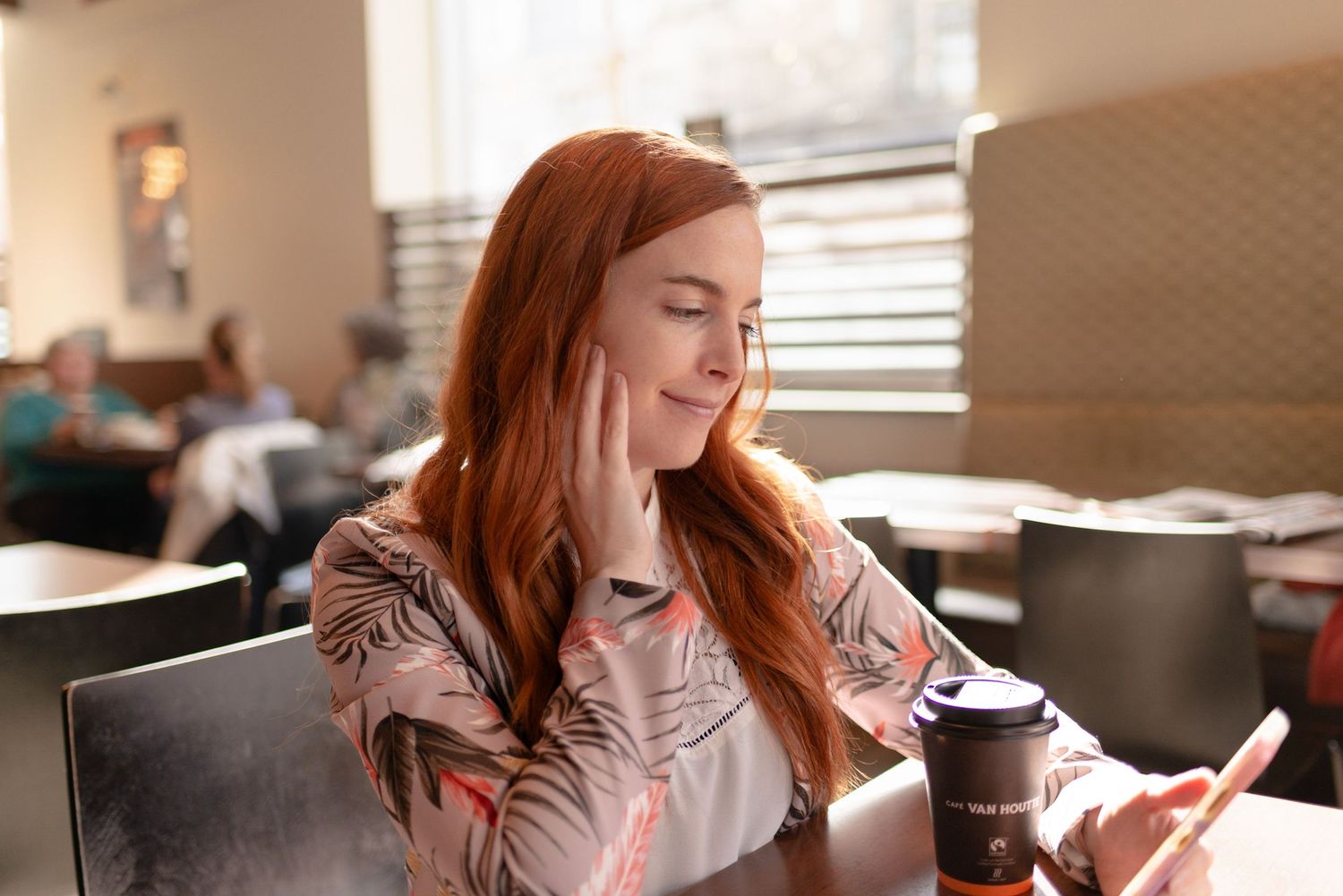Woman with long hair relaxing and smiling while reading indoors.