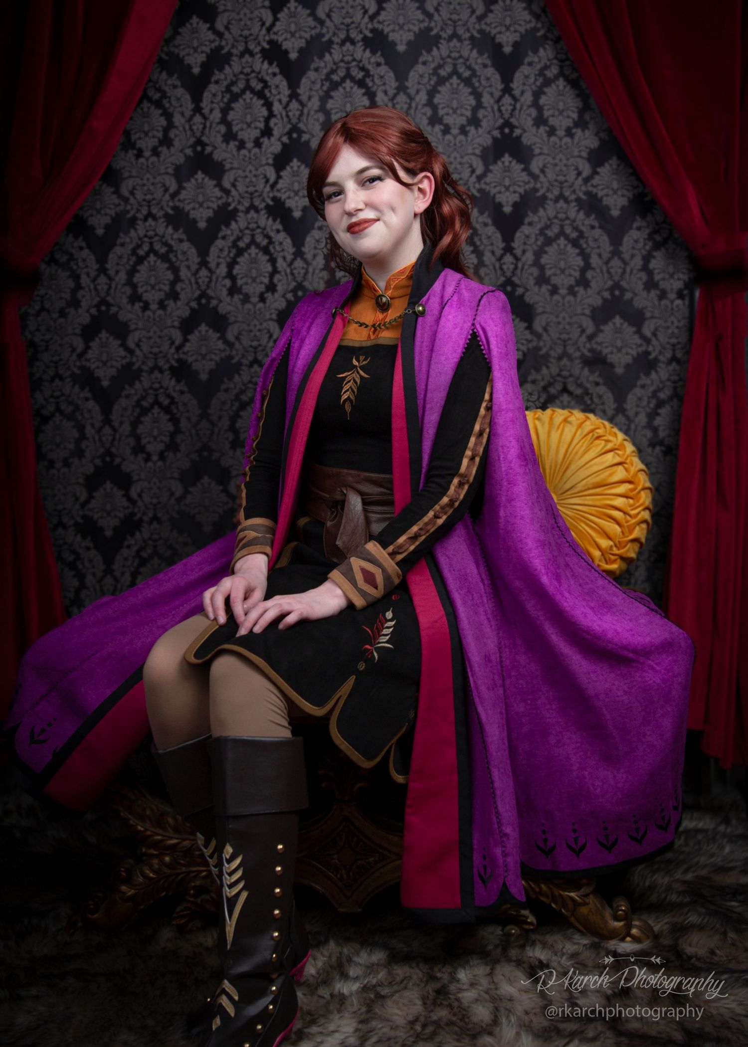 Cosplay portrait against damask wallpaper featuring purple coat and vintage-inspired costume.
