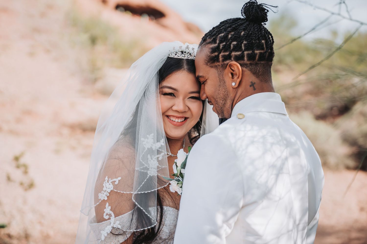 An intimate wedding portrait showing a joyful moment between newlyweds in a desert setting.