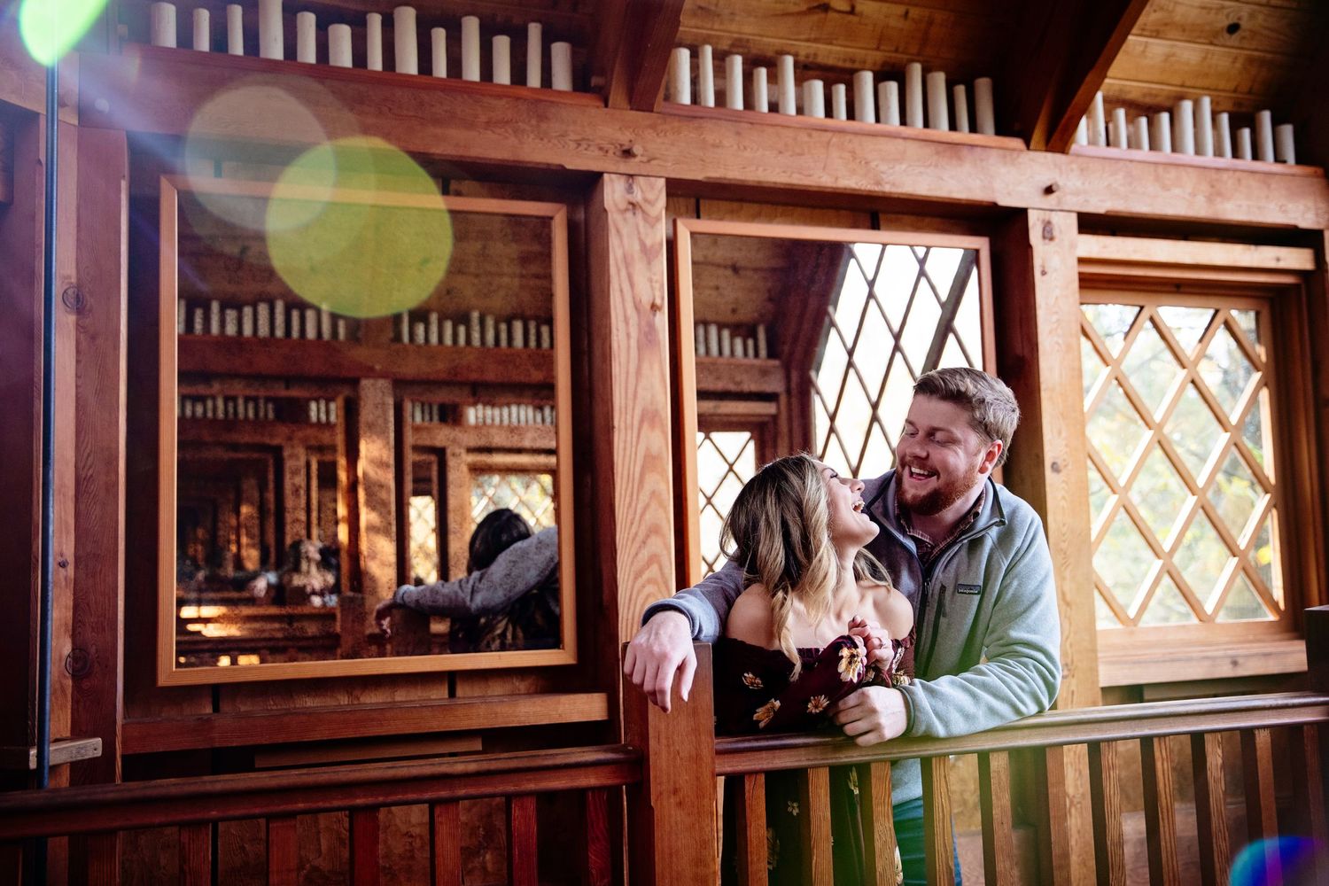 A couple sharing an intimate moment on a wooden balcony with lens flare.