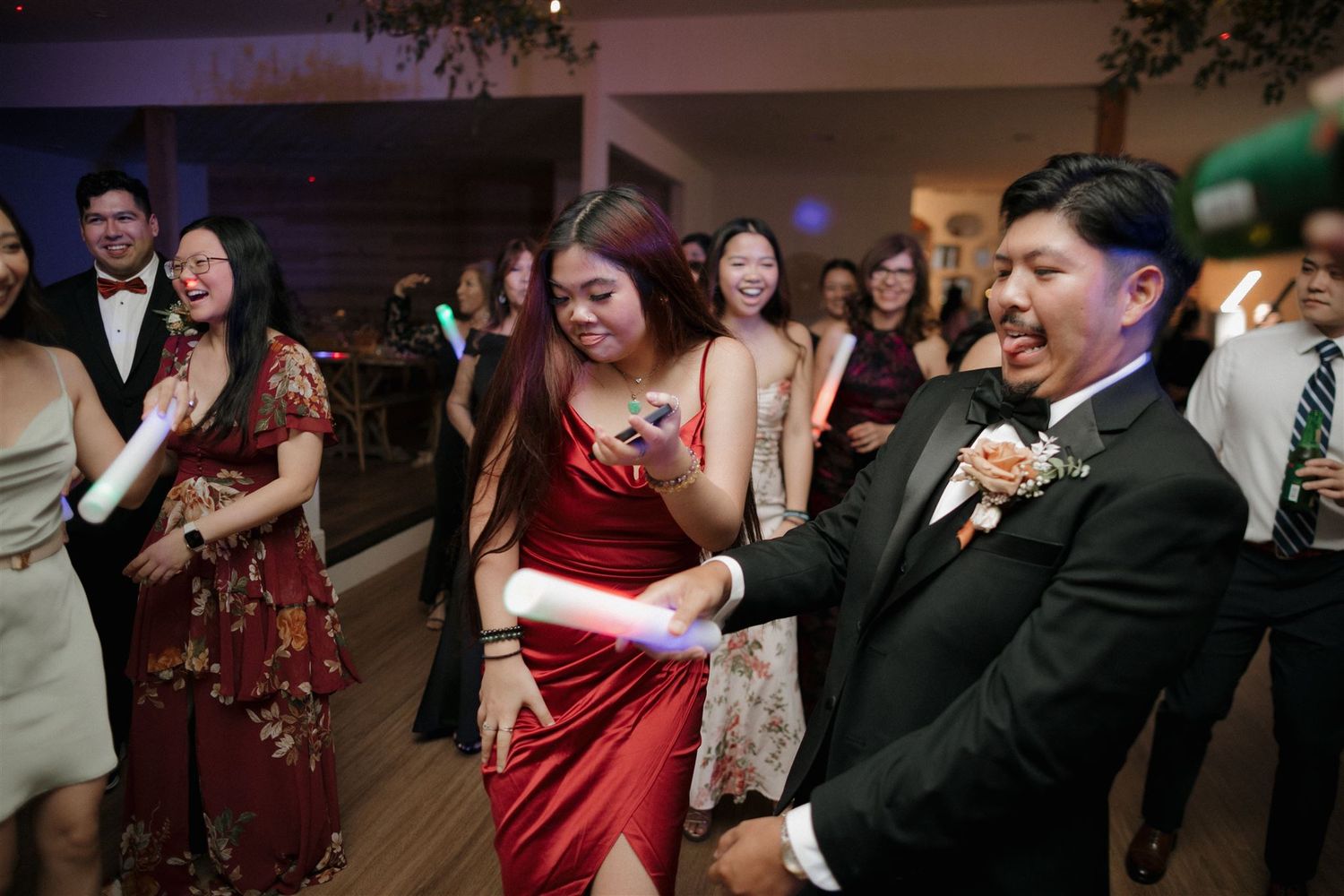 Wedding guests dancing and celebrating in formal attire at an indoor reception.