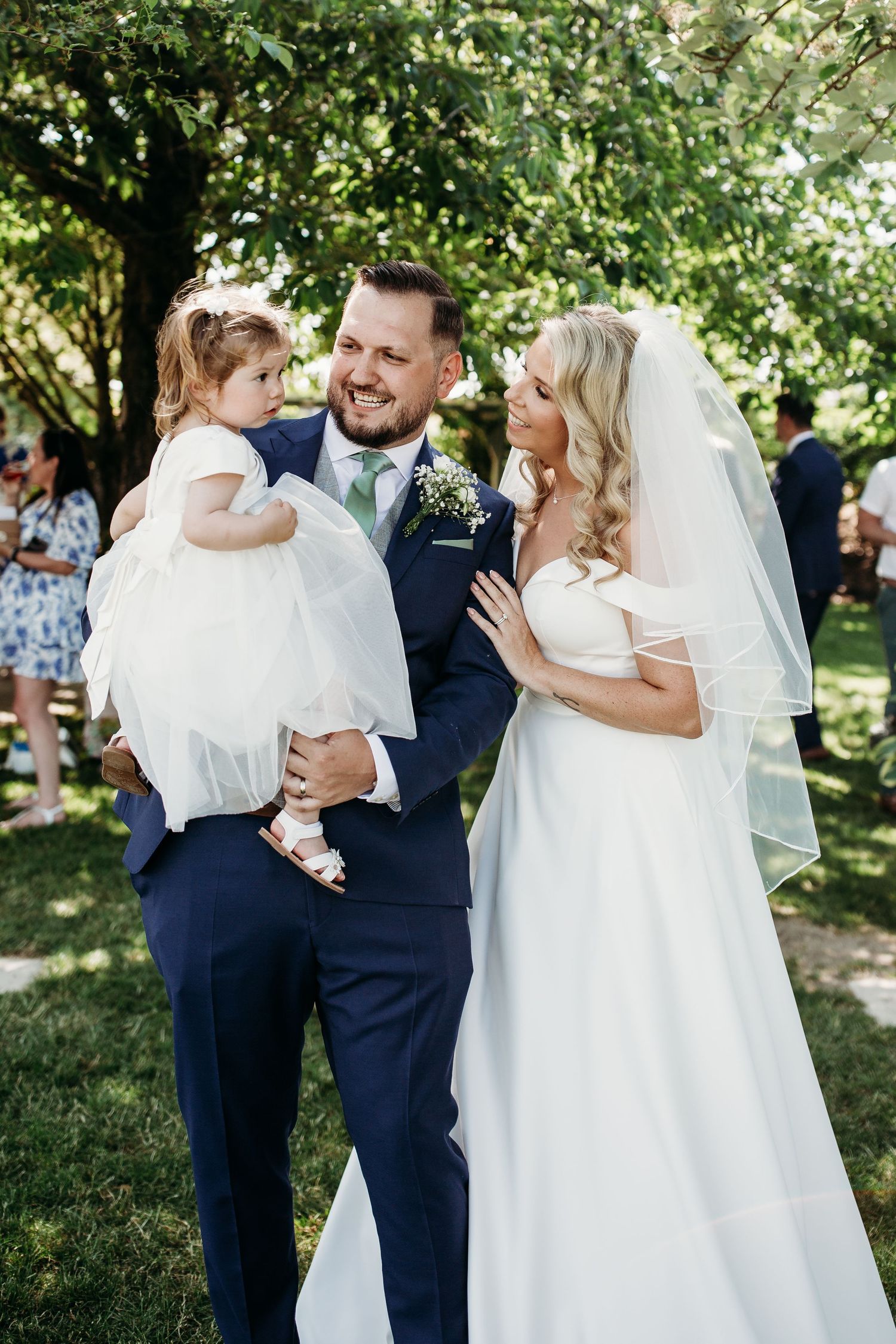 Outdoor wedding celebration with family on sunny garden lawn.