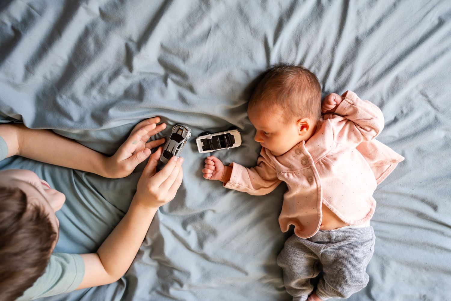 brother showing newborn sister hotwheel cars