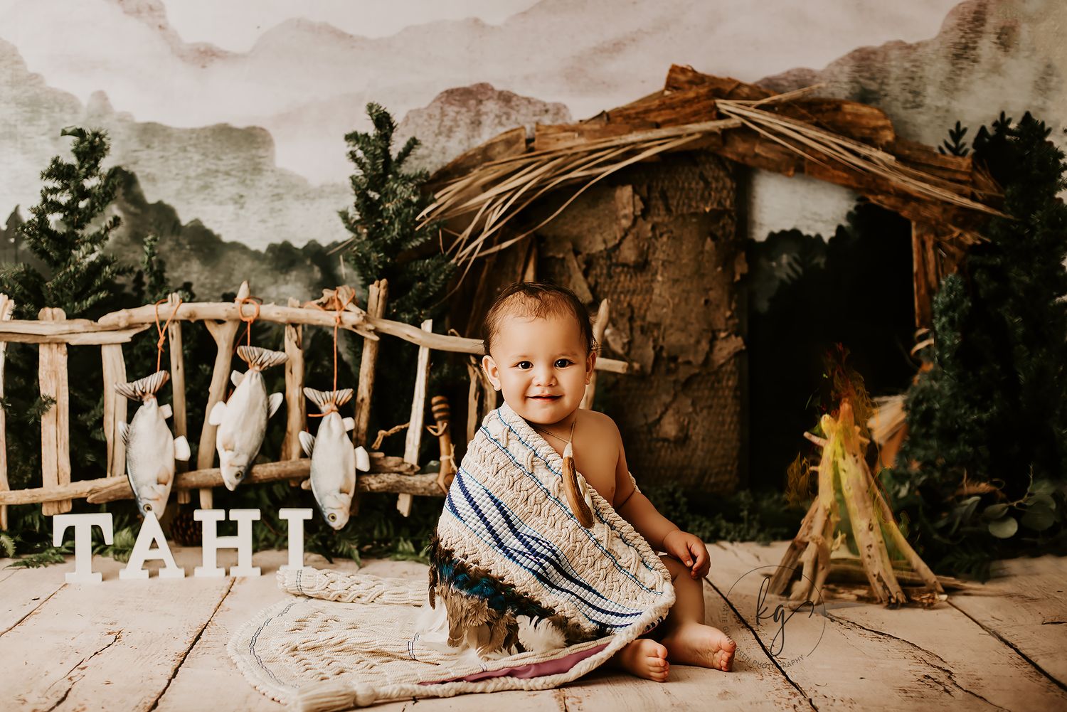 Small child sitting on rustic wooden set with nativity scene backdrop.