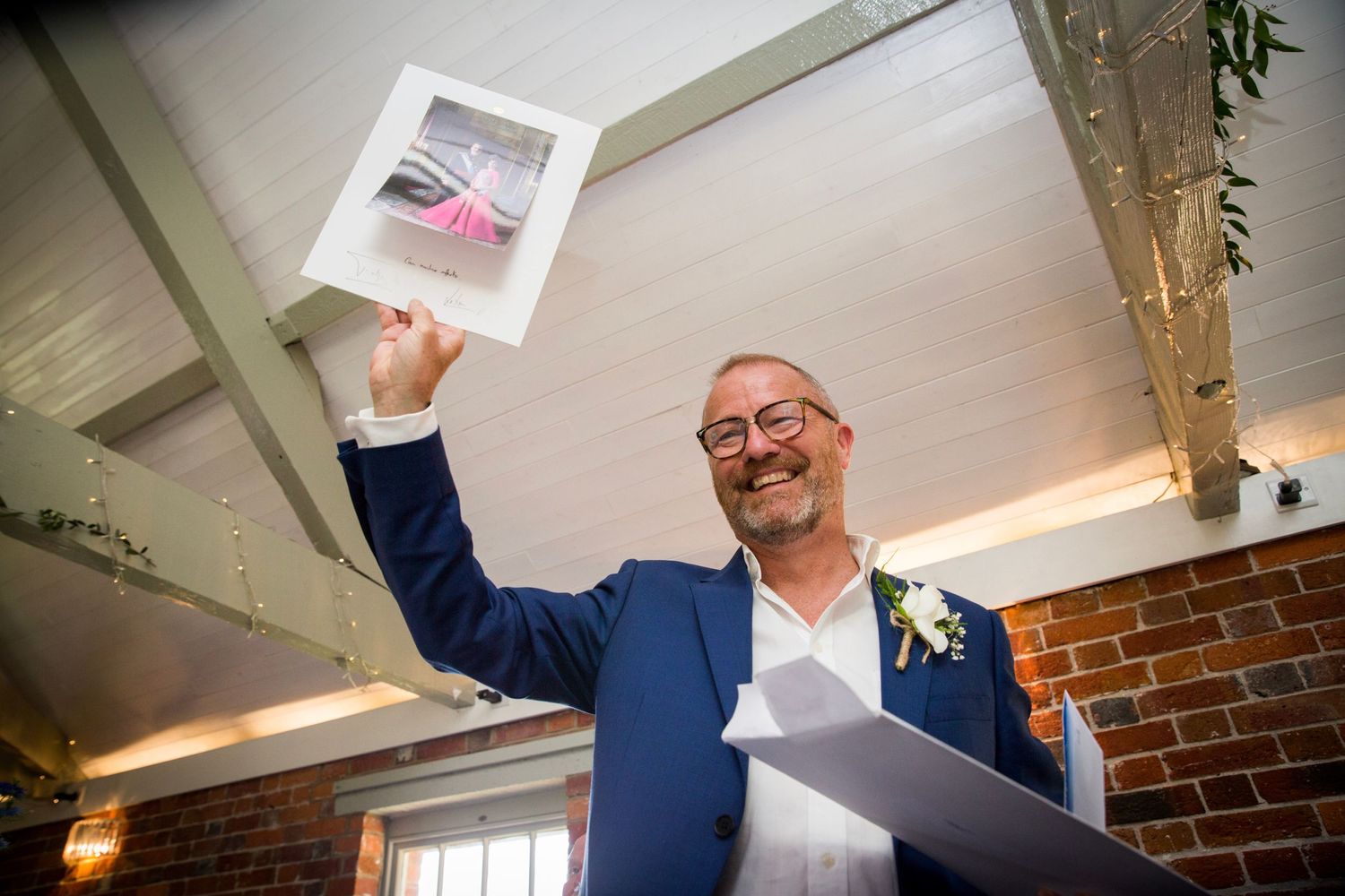 Wedding guests sharing laughter while looking at photographs during reception.