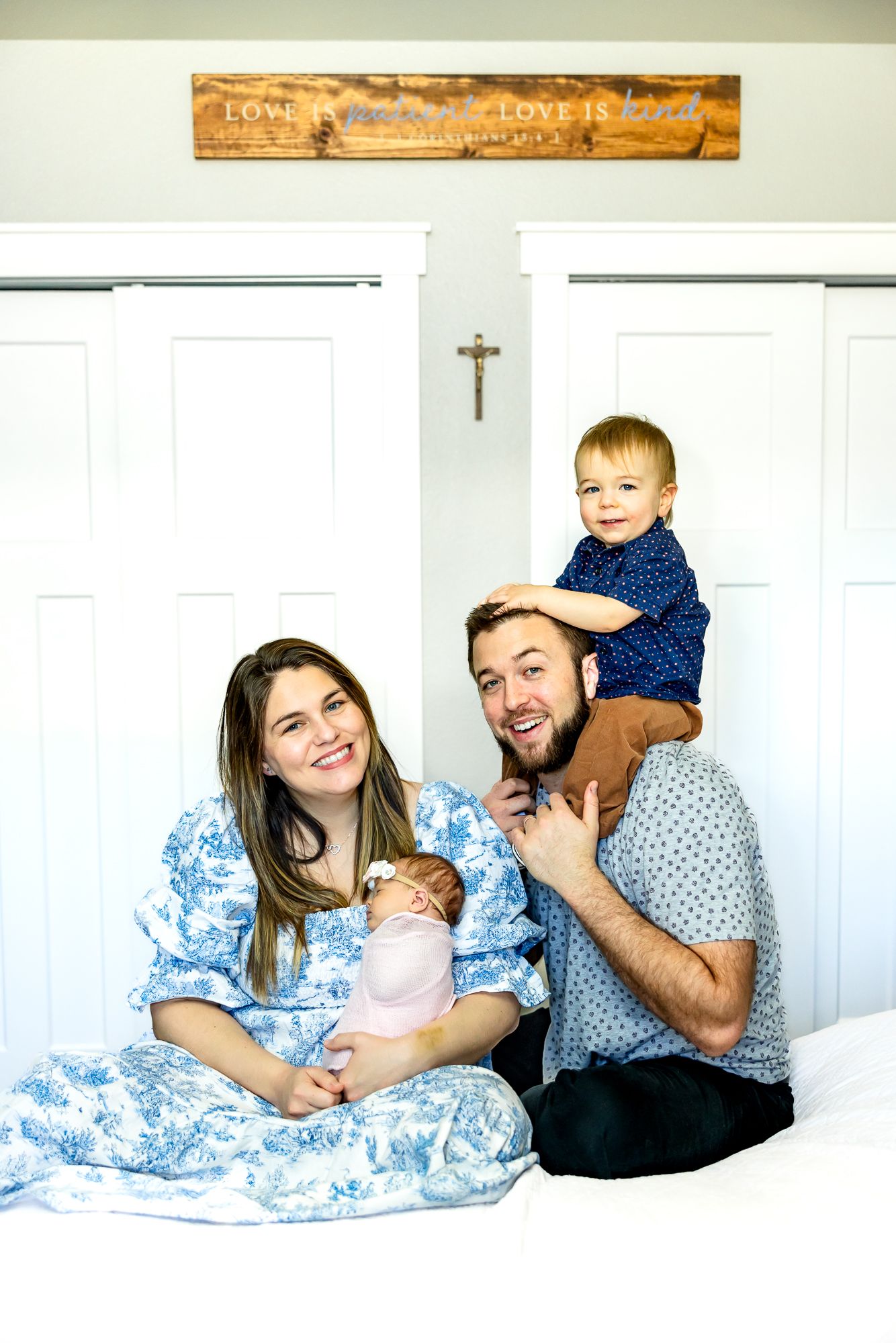 Parents smile with toddler boy on dad's shoulders and baby girl in mom's arms during newborn photos in Colorado Springs.