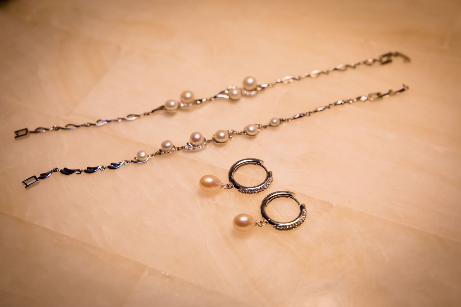 Delicate pearl and crystal bridal jewelry displayed on soft beige background.