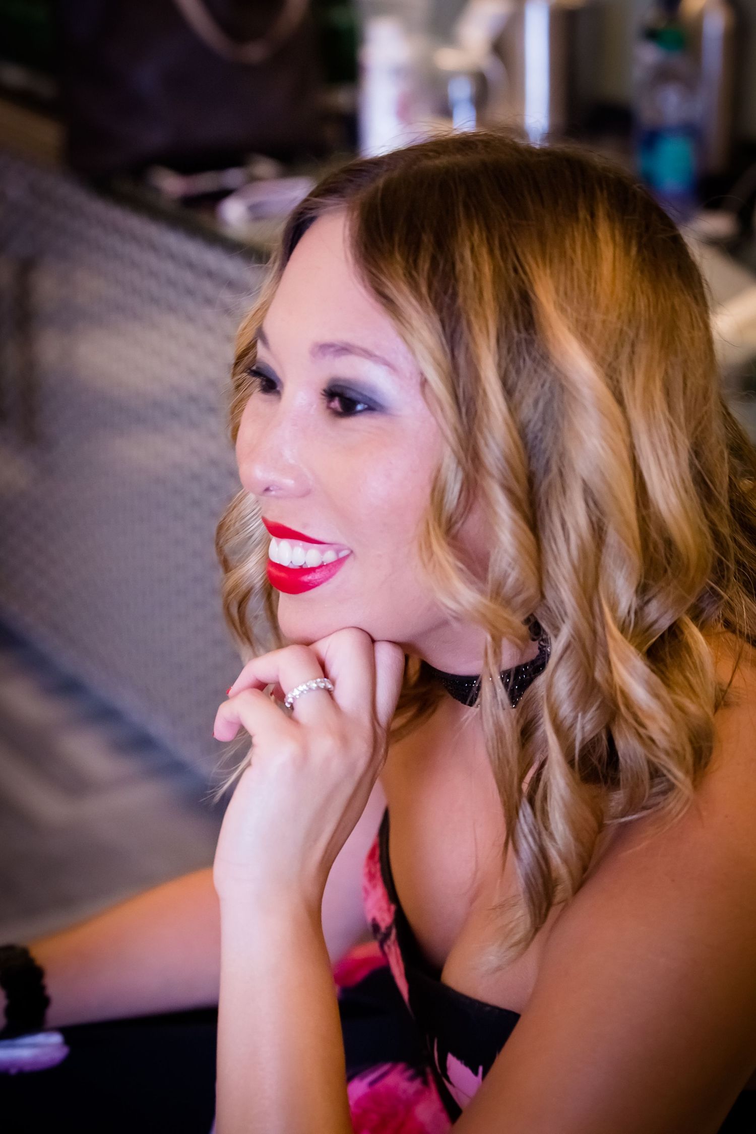 Glamorous portrait showing wavy hair and bright red lipstick in soft lighting.