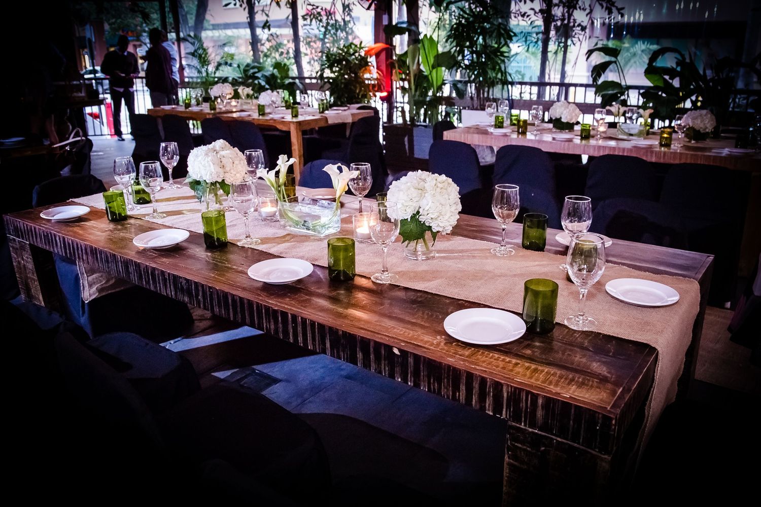 Long wooden dining tables set up for an evening event with ambient lighting.