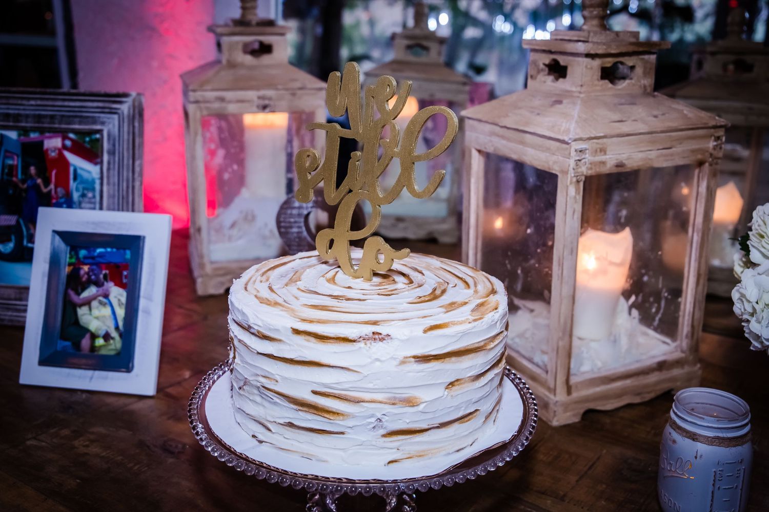 Wedding cake display with rustic decorations and string lights.