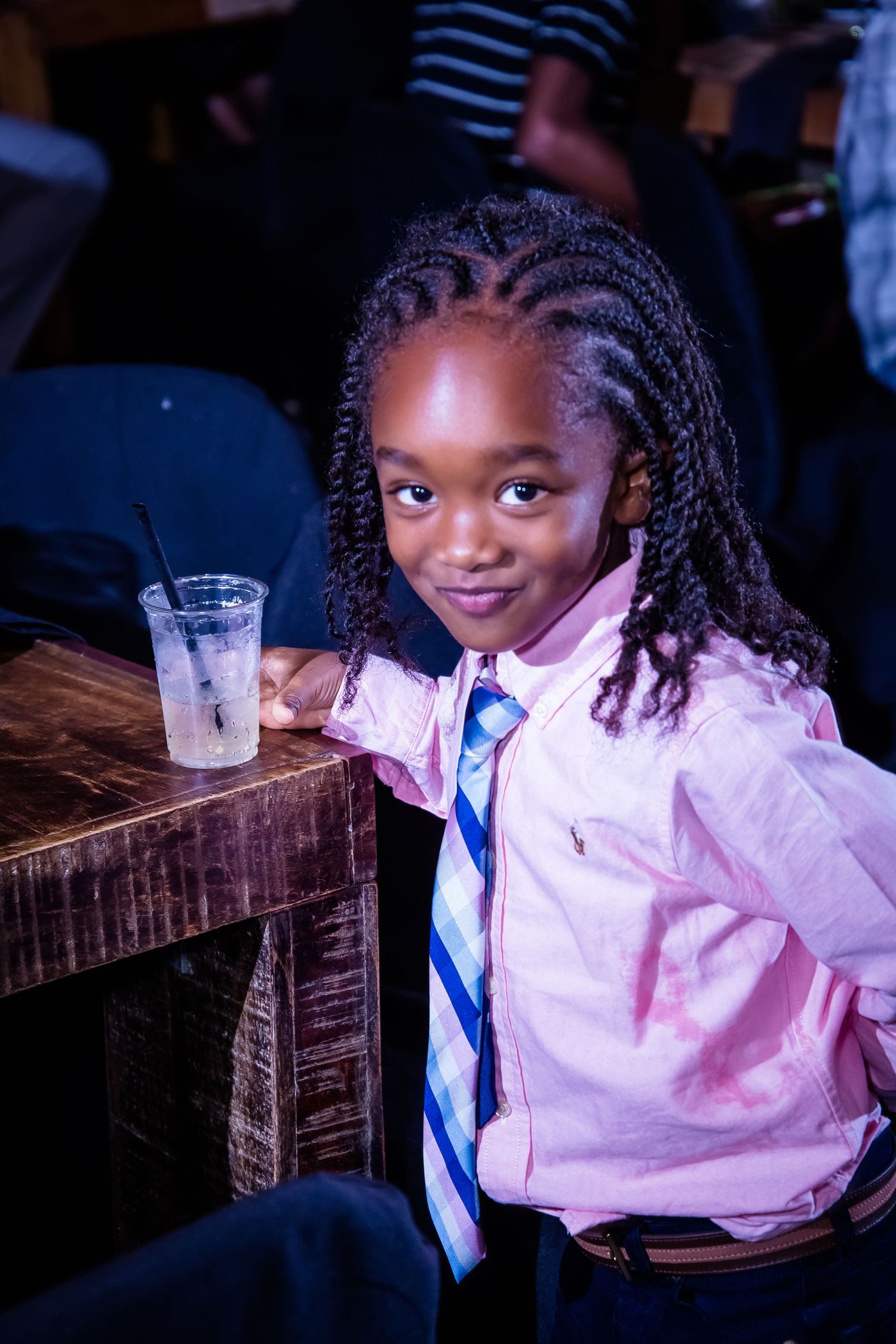 A child in formal attire smiling brightly at a social gathering.