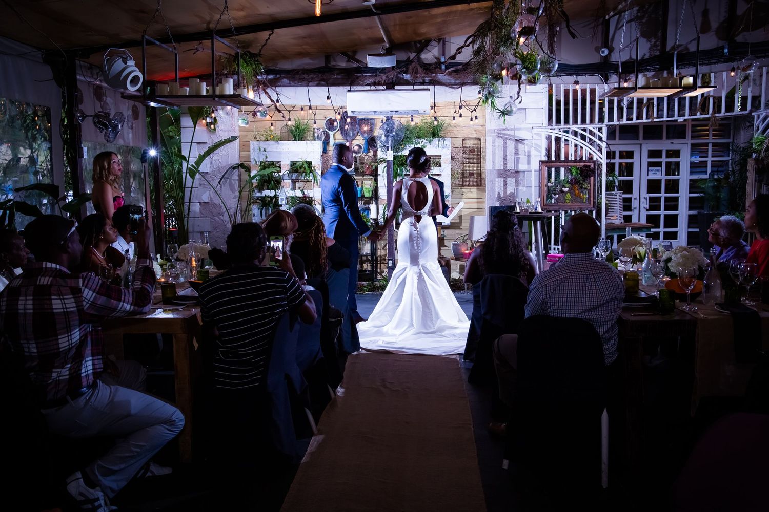 Silhouette of wedding ceremony in a dimly lit venue with decorative lighting.
