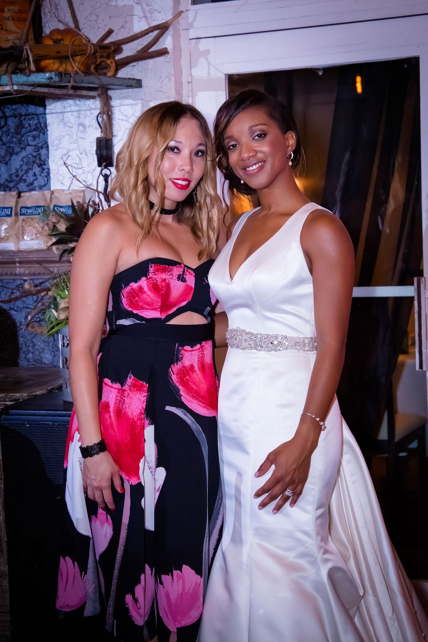 Wedding celebration with guests in formal attire including black dresses with pink accents and white gowns.