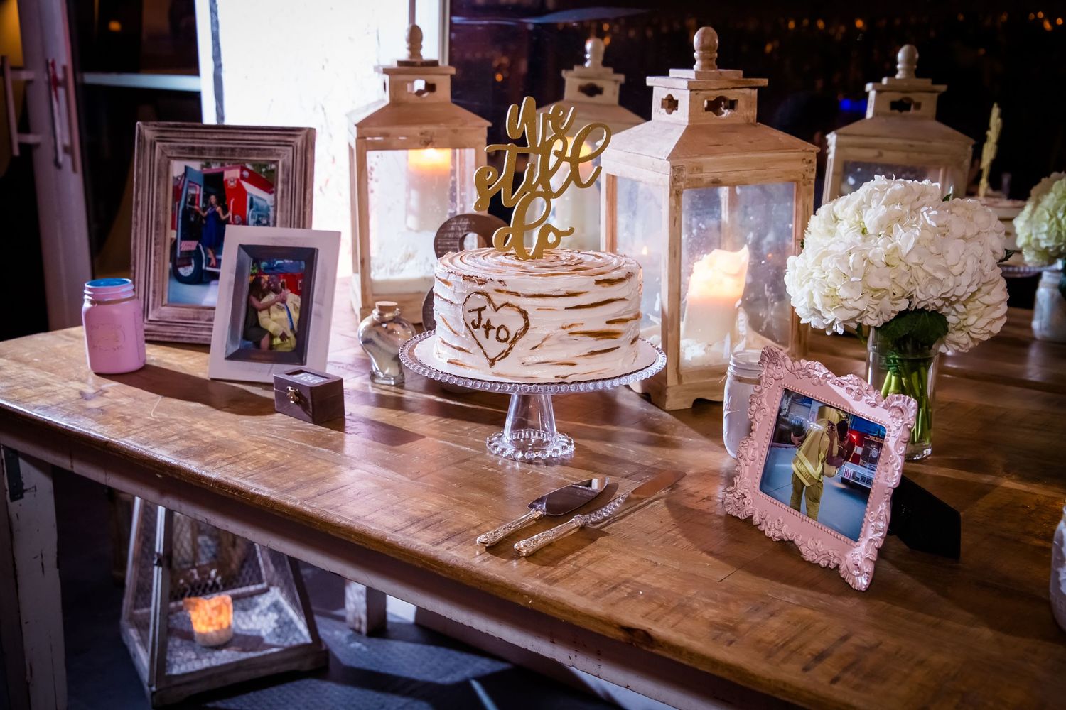 Rustic wedding reception table with cake display and wooden decor elements.