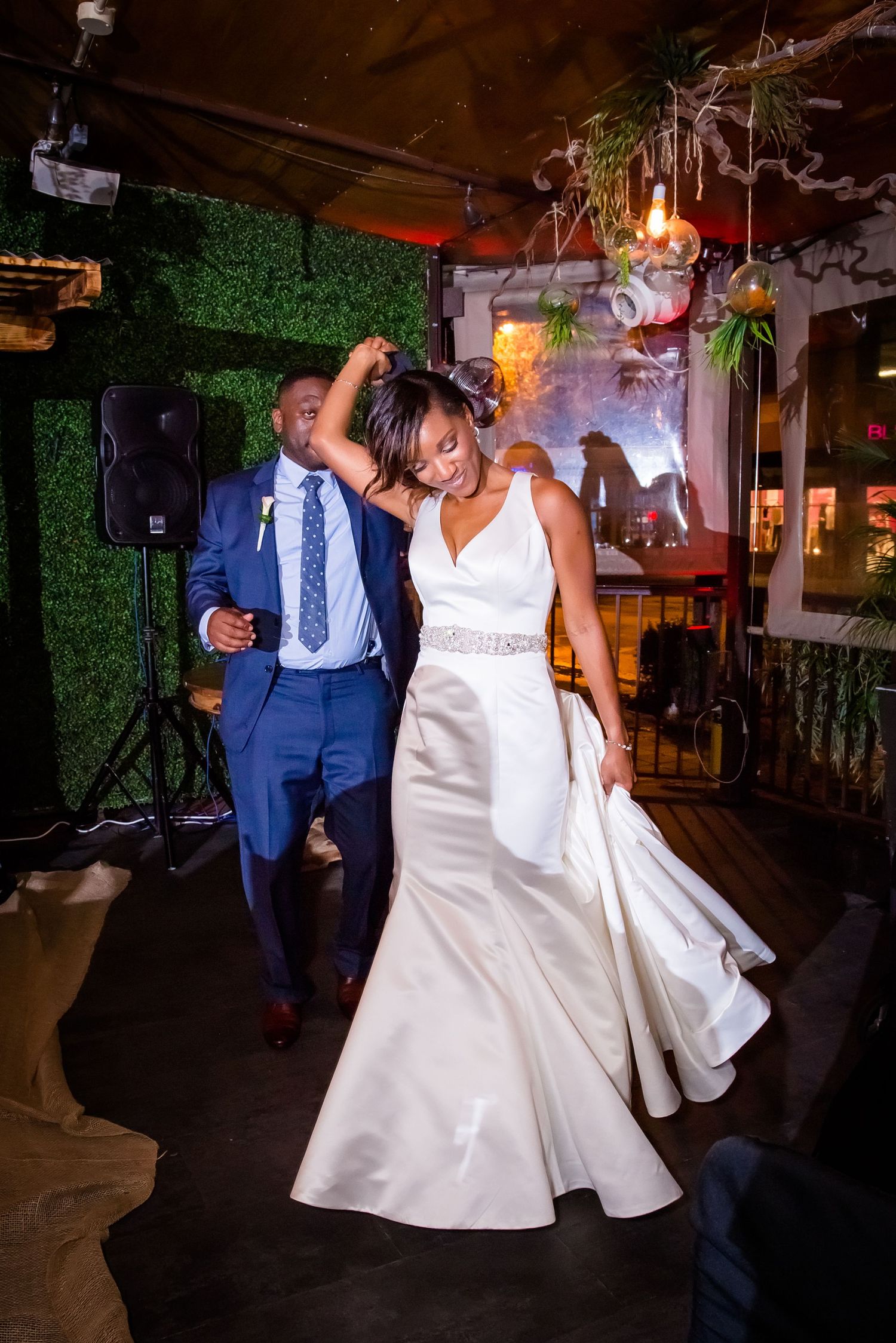 Newlyweds sharing a romantic dance moment on their wedding day in a dimly lit rustic venue.