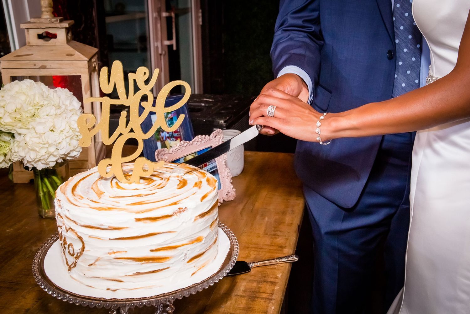 Elegant white wedding cake displayed on wooden table at reception.