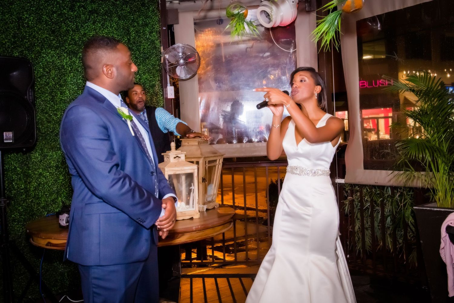 Bride and groom dancing together under decorative lighting at their wedding reception.