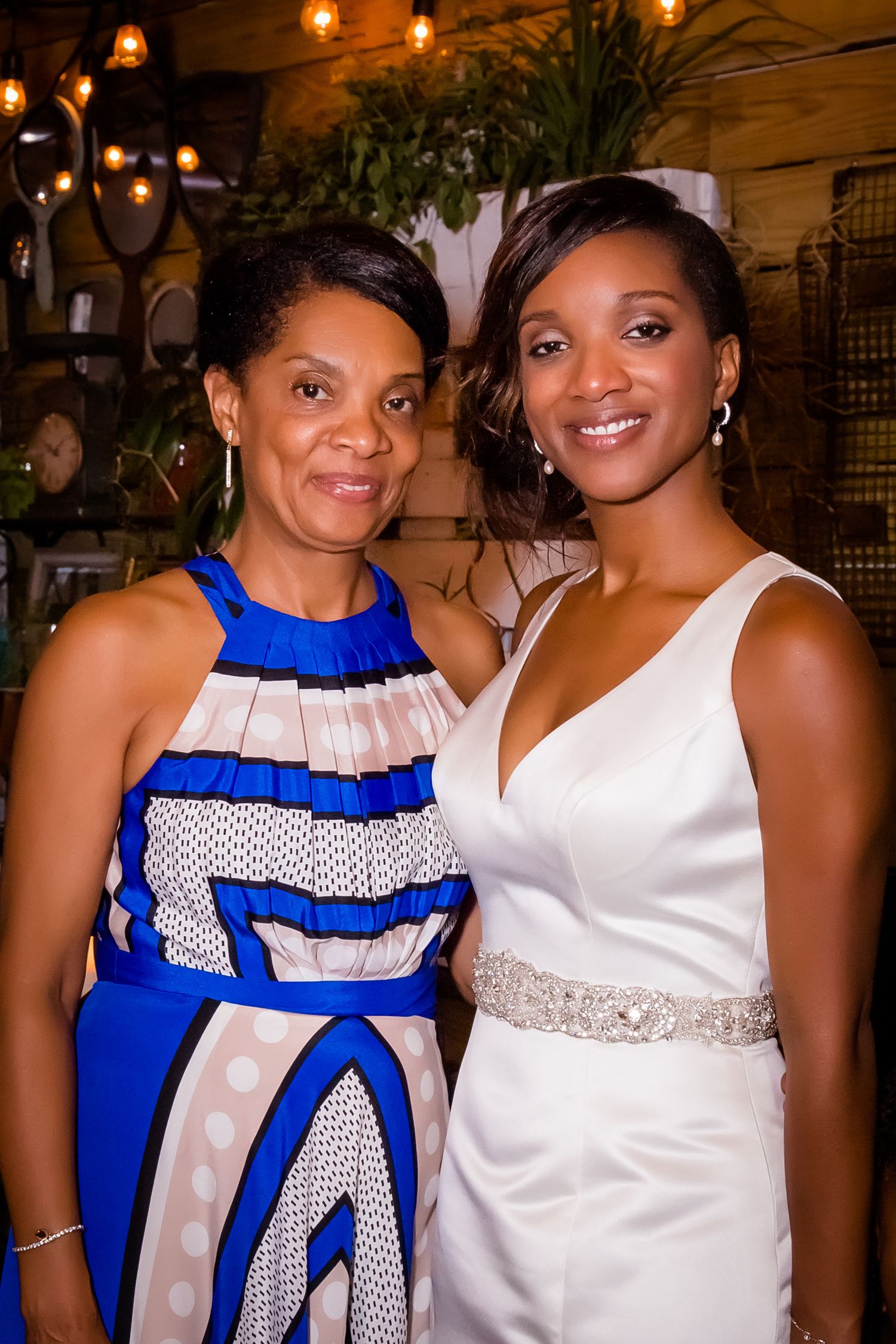 Two guests in formal attire posing together at a wedding reception with blue and white color coordination.