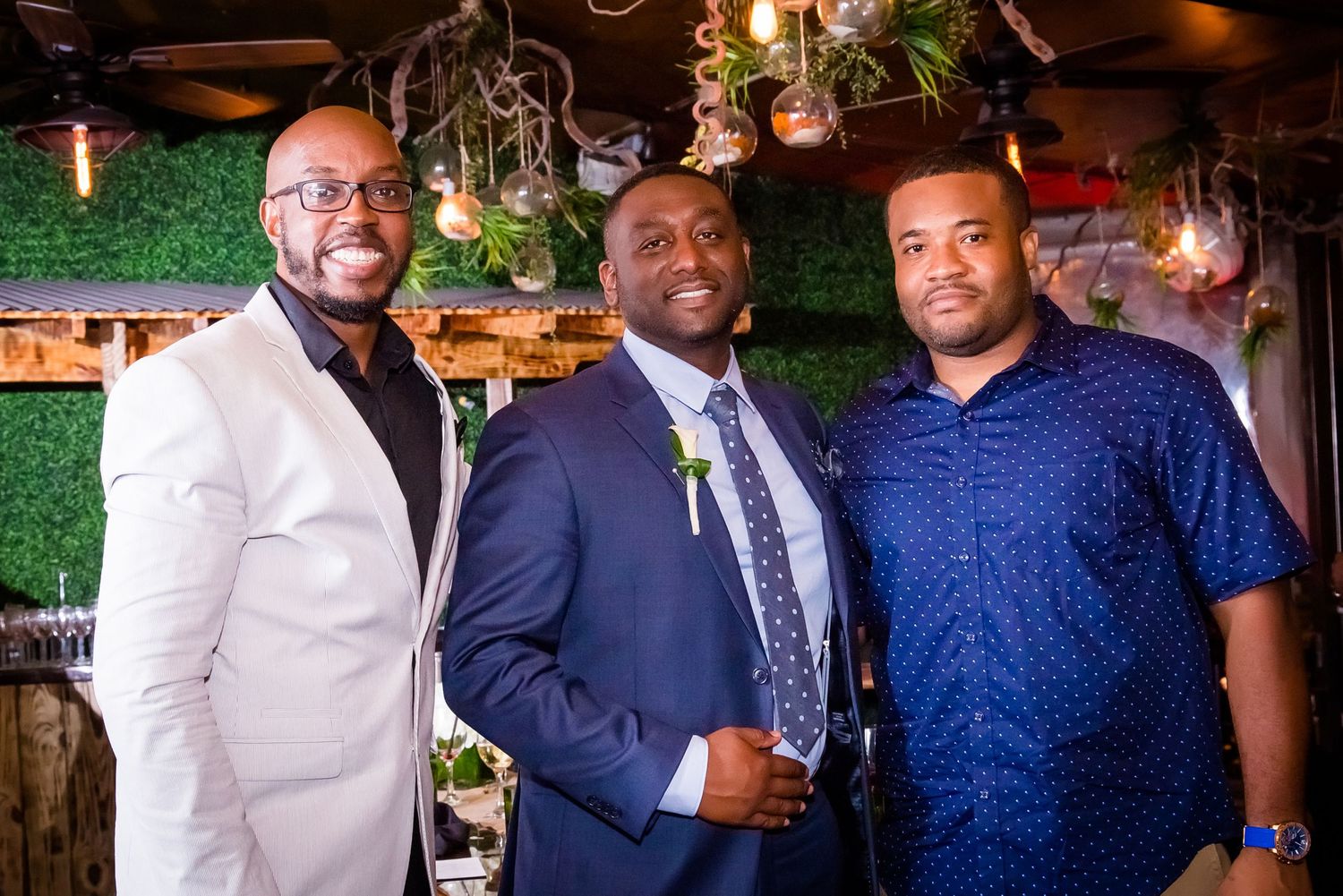 Group of wedding guests in formal attire gathered at an indoor reception venue.