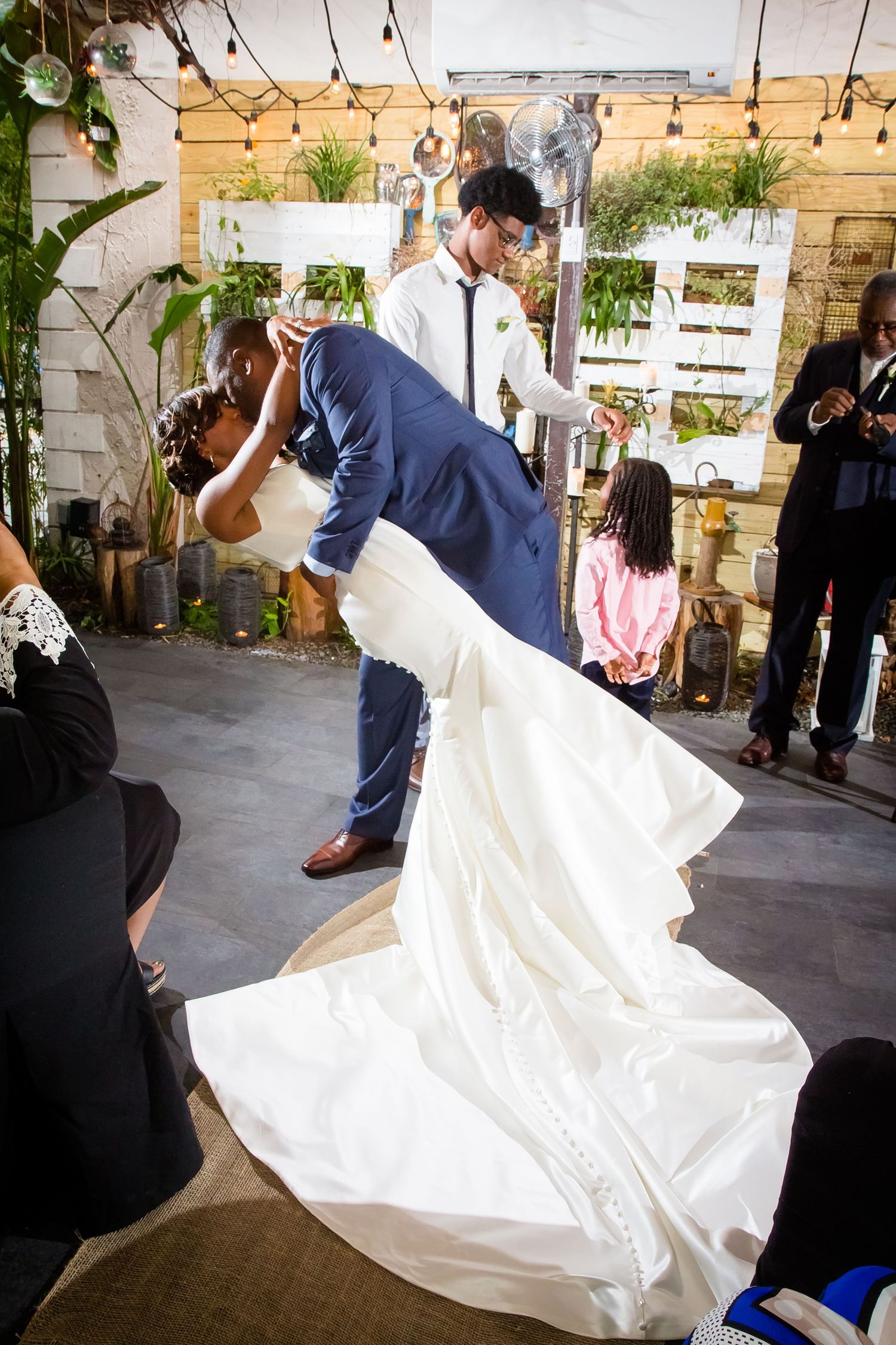 Bride's white wedding dress flowing during a dance in a venue decorated with string lights.