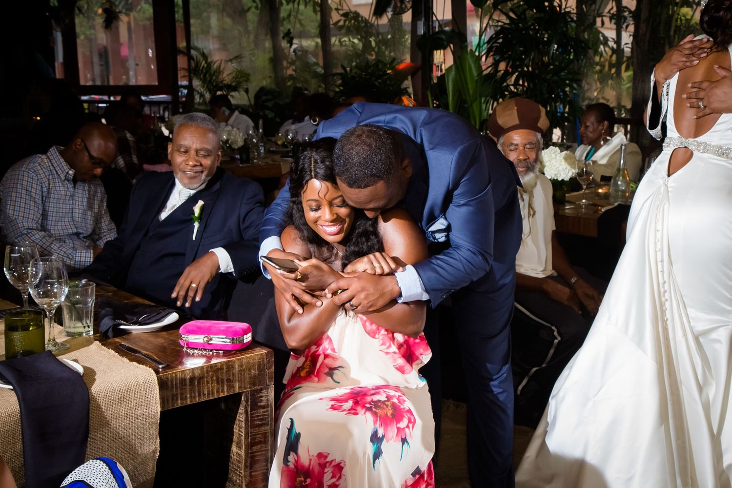 Wedding reception guests mingling in a rustic venue with romantic lighting and floral decorations.