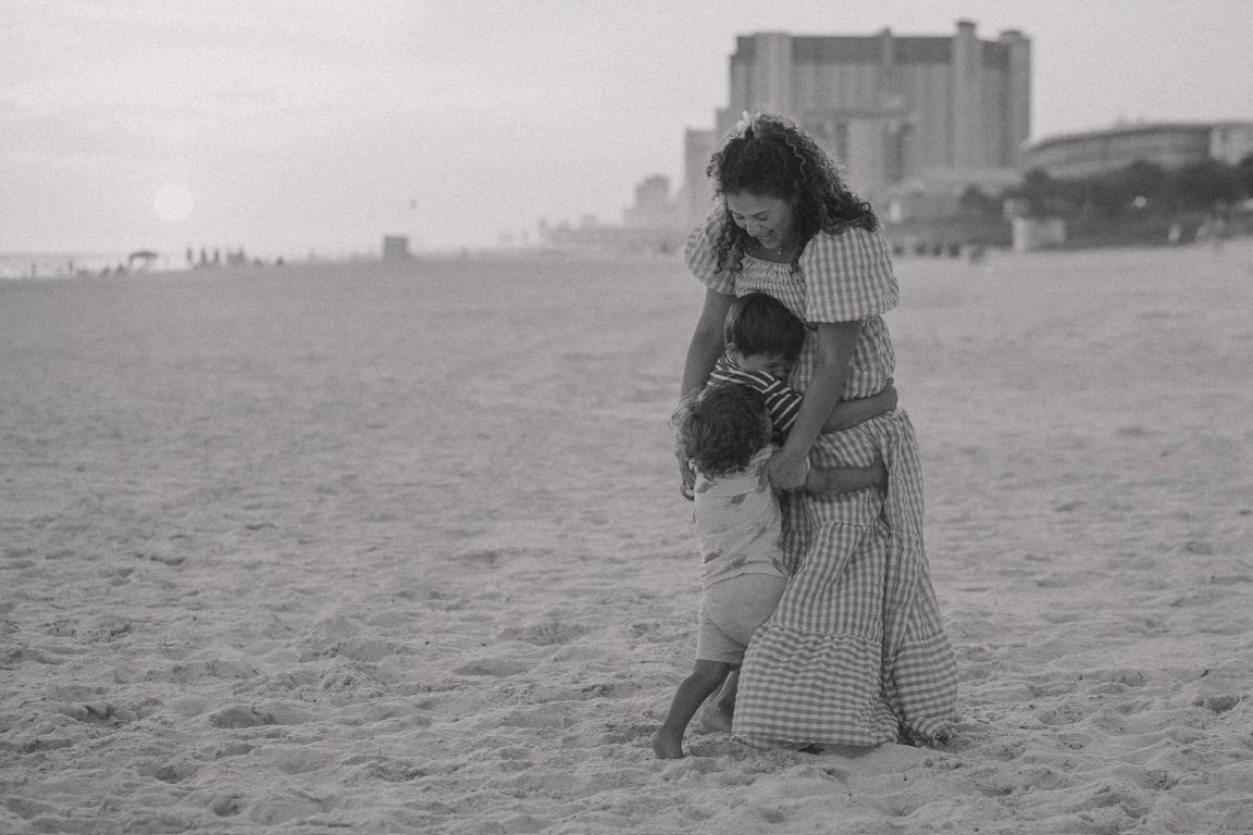 Vintage black and white beach scene with couple embracing on sandy shore.