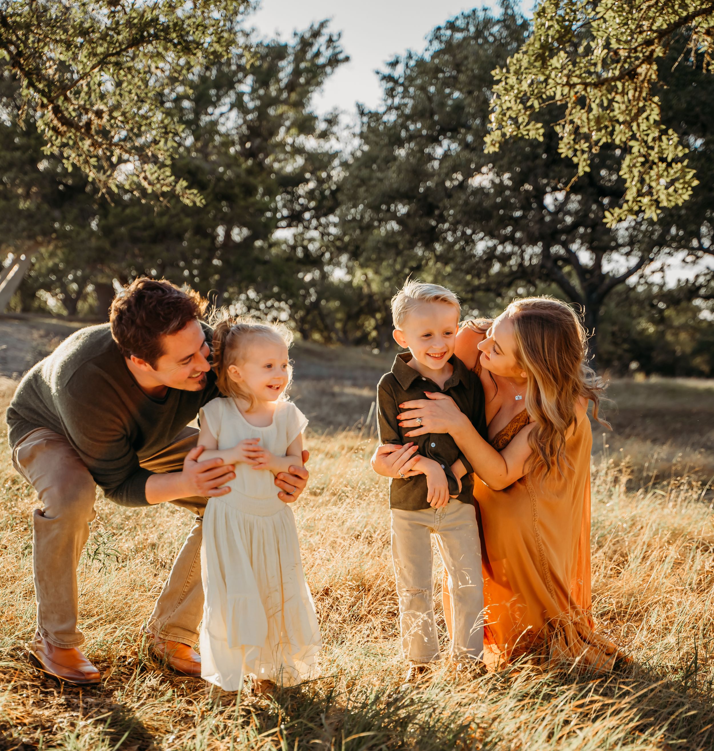 Family gathering in golden field during sunset with warm lighting.
