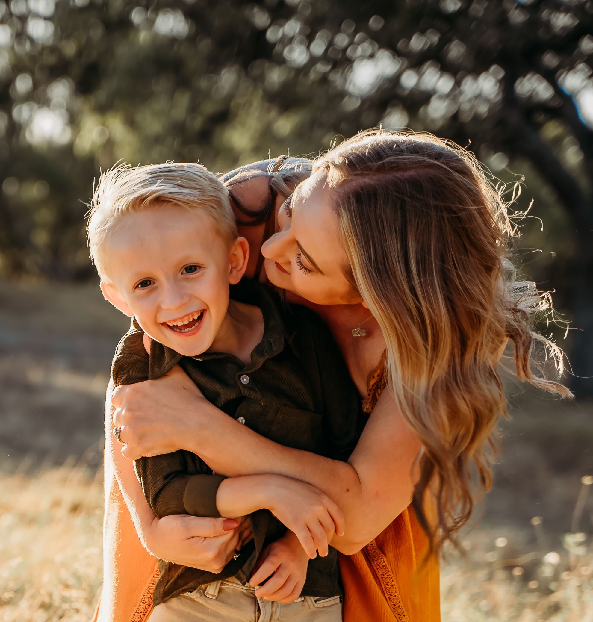 Tender moment between parent and child in warm sunlit field.