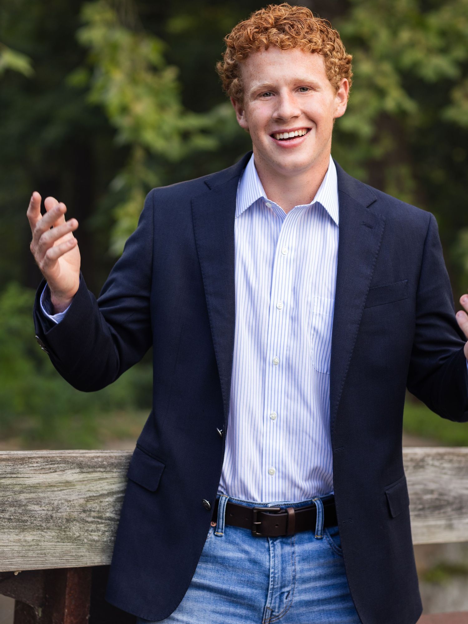 senior boy in blue jacket with hands up
