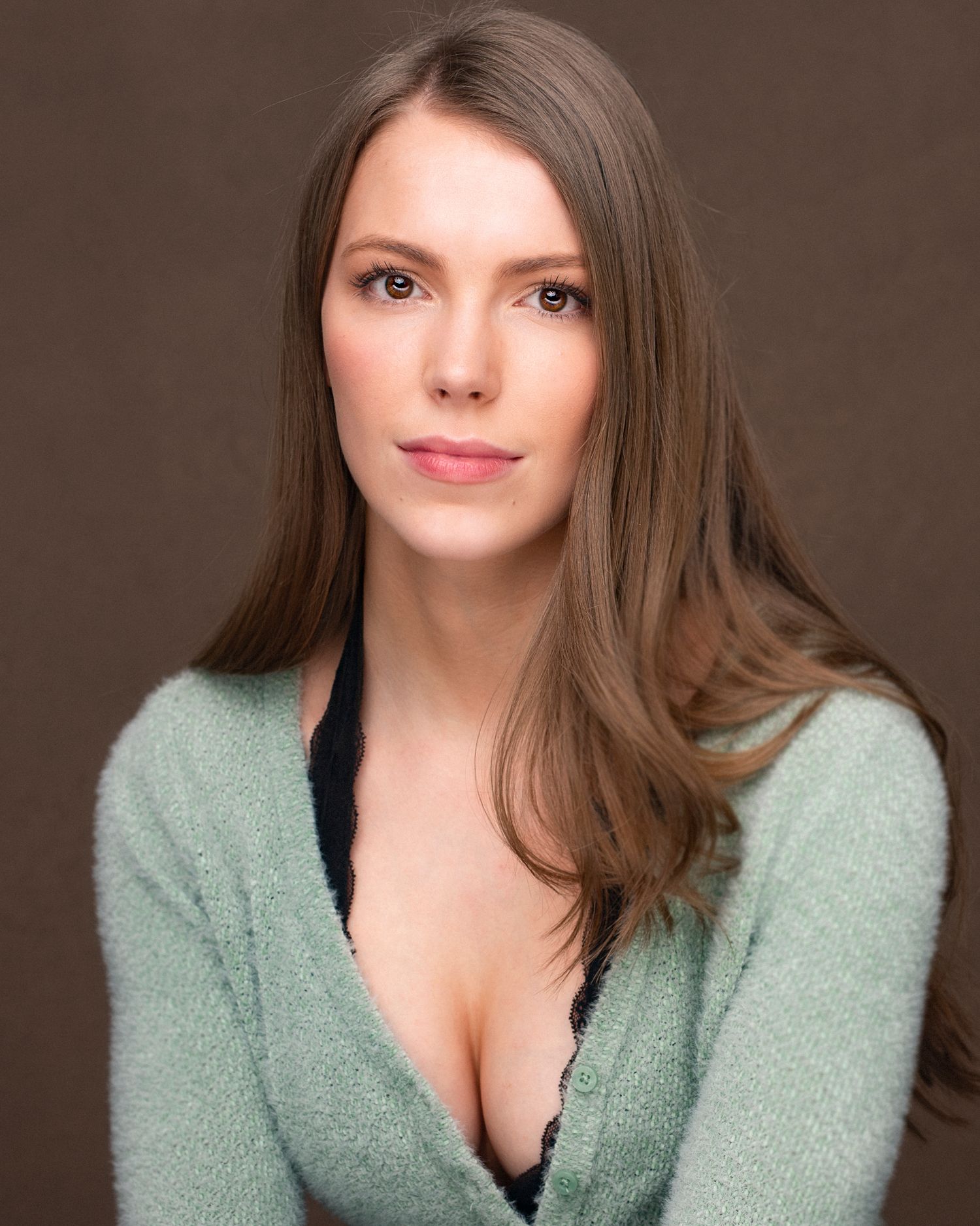 Studio portrait showing a person in a mint green sweater against a dark background.