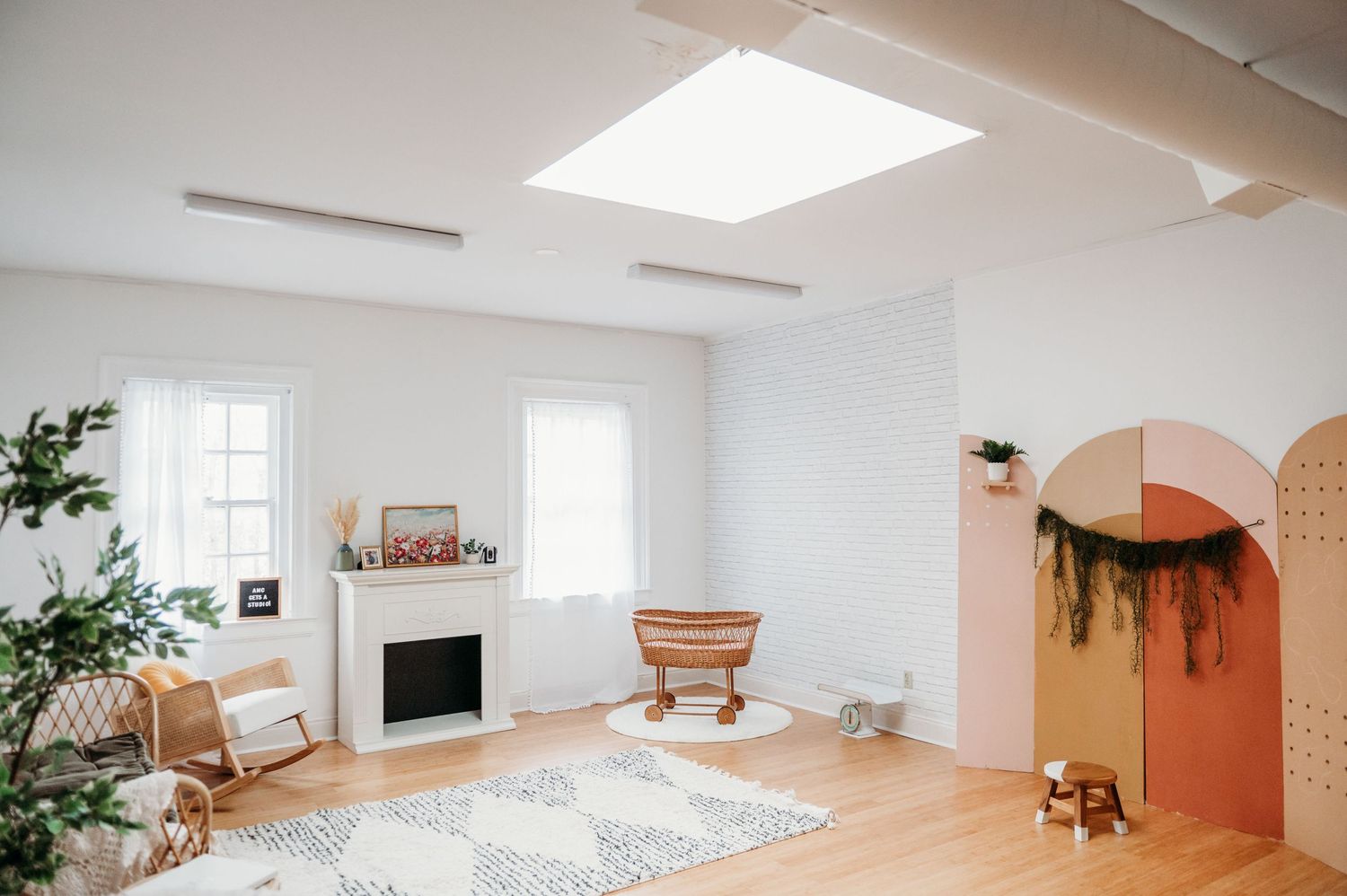 Modern minimalist living room with white walls, arched doorway, fireplace, and skylights features warm terracotta accents.