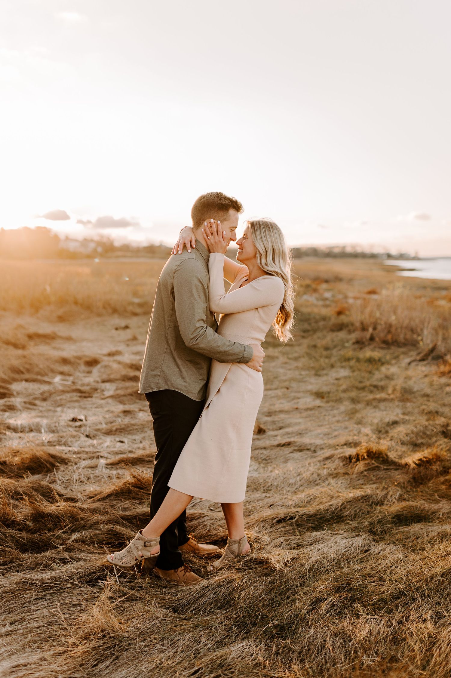 A romantic moment captured between two people in a field during golden hour.