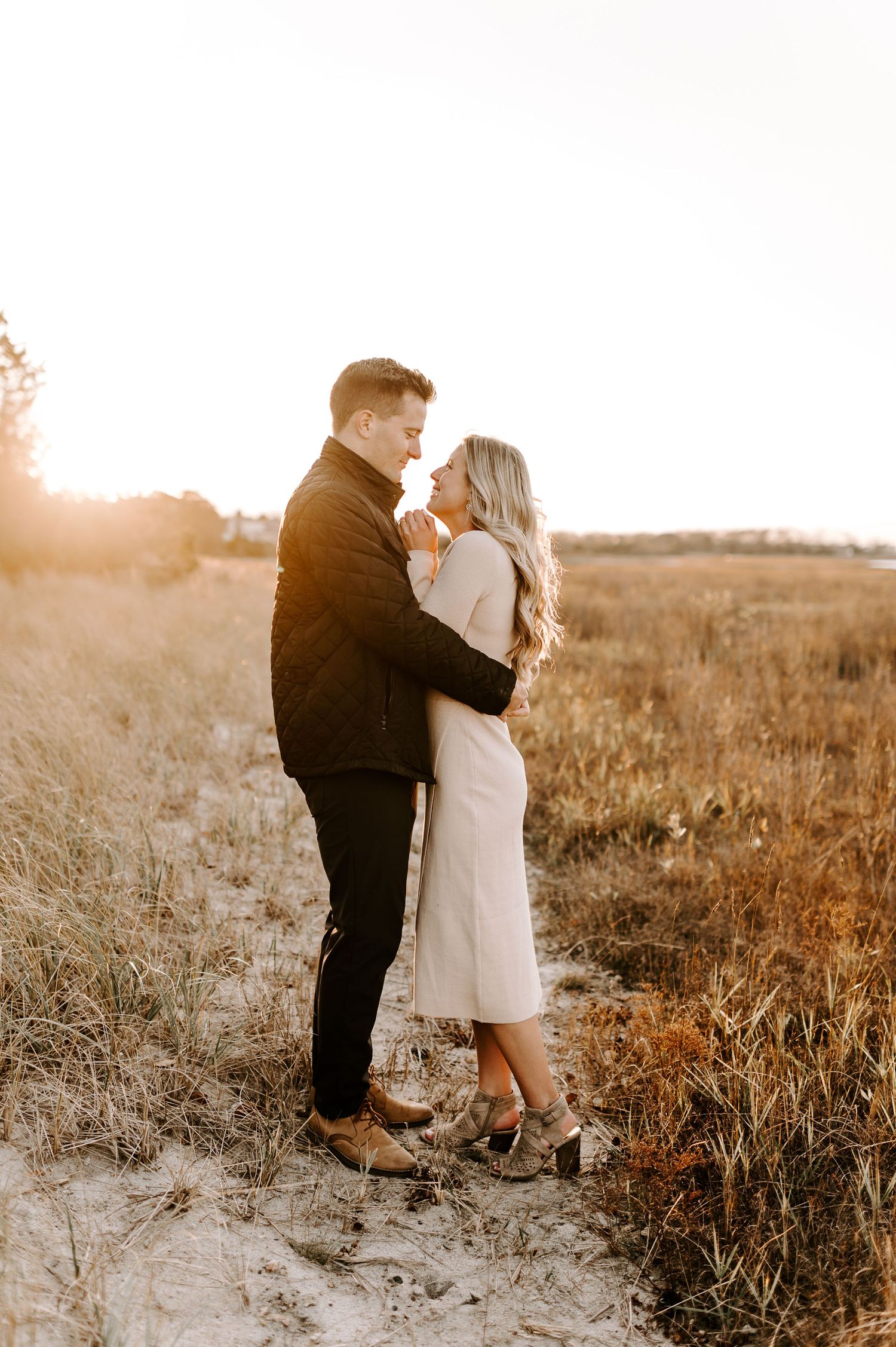 A couple embraces in a golden field during sunset, creating a romantic silhouette against the warm light.